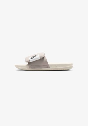 Sandalo slide beige Nike con cinturino imbottito regolabile con logo Nike nero, suola piatta e sottile logo swoosh in rilievo sul lato.