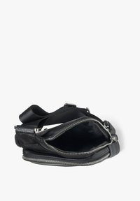 Černá kožená křížová taška se zipovým uzavřením, s texturovaným povrchem, nastavitelným popruhem a metalickými akcenty.