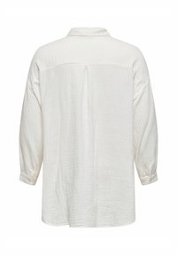 Chemise blanche à manches longues en tissu texturé et froissé, avec des poignets boutonnés et un détail de patte de boutonnage au dos. Elle présente un col classique et une coupe décontractée.
