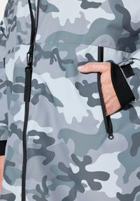 Grå kamouflagejacka i smidigt tyg med en zipficka, elastiska muddar och en kontrasterande svart dragkedjedetalj.