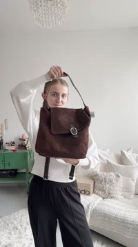 Rjavi tkaninski nahrbtnik z zložljivim pokrovom, srebrnimi kovinskimi detajli, odstranljivimi naramnicami in teksturirano površino. Kompaktna in praktična zasnova.