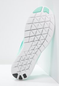 Suola di scarpa sportiva in teal chiaro con un fondo di gomma bianca testurizzata, caratterizzata da un motivo del battistrada geometrico e dettagli neri sul tallone.