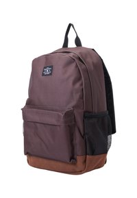 Mochila de tela marrón con un bolsillo lateral de malla negra, bolsillo frontal plano y fondo marrón reforzado. Cuenta con un asa superior y correas ajustables.