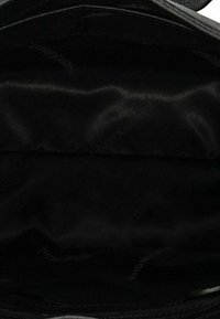 Intérieur de sac à main noir vide avec doublure en tissu lisse visible et motif subtil de texte de marque.