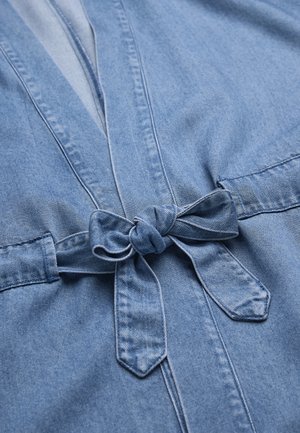 Lichtblauw denim kledingstuk met een strik aan de taille, met gestikte naden en een zachte stoftextuur.