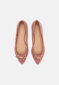 Rosa mockaskinnsballetskor med spetstå, med en dekorativ guldbåge framtill och en beige innersula.