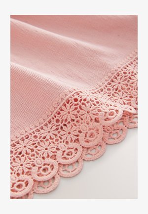 Tela rosa con una superficie texturizada, que presenta un delicado encaje con patrones circulares a lo largo del borde. Color suave y pastel.