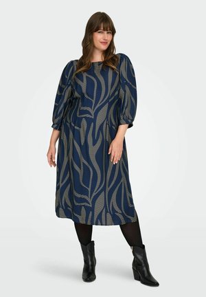Vestido azul marino con rayas doradas abstractas, mangas abullonadas y una silueta en A. Combinado con botines negros y medias opacas.