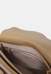 Borsa a mano in pelle tan con un esterno morbido e testurizzato, dettagli in metallo dorato e un interno chiaro, comprensivo di una tasca con zip.