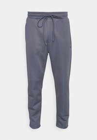 Grey jogger pants with a drawstring waist, tailored fit, and smooth texture. Features side pockets and a subtle logo accent.