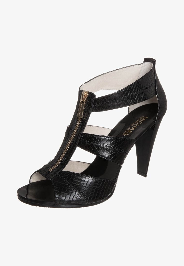 Sandale à talon haut noire avec un design à bout ouvert, en matériau texturé effet serpent, ornement de fermeture éclair dorée et brides ouvertes autour de la cheville.