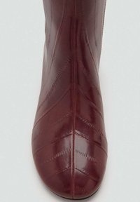 Burgundi nahkajalkine, jossa on terävä kärki. Sisältää teksturoitua vinoa ommelta, sileän pinnan ja solakan siluetin.