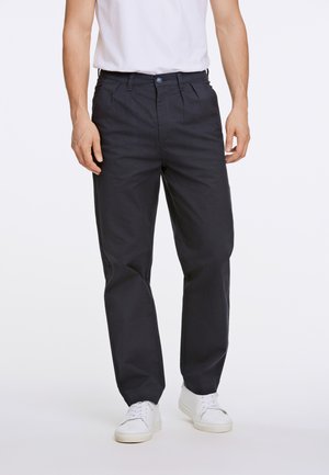Navyblauwe katoenen broeken met een rechte pijp, voorplooien en een knoopsluiting, gecombineerd met witte sneakers.
