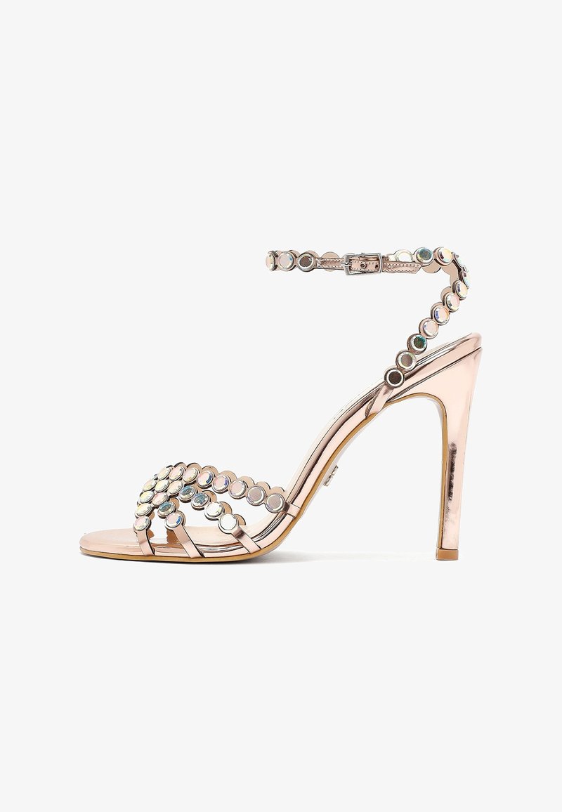 Rose gold high-heeled sandal with ankle strap, decorated with circular reflective studs along straps and heel.