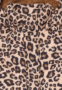 Piepildīta jakas ar bēša audumu, kas rotāts ar brūnu un melnu leoparda rakstu, ar quilted dizainu un augstu apkakli.