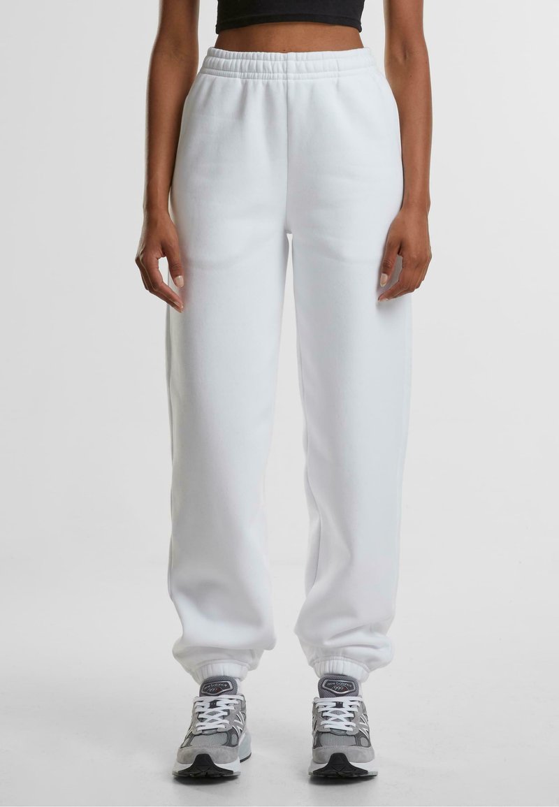 Witte trainingsbroek met een elastische tailleband en boorden, voorzien van een gladde textuur. Gekozen in combinatie met grijze en witte sport sneakers.