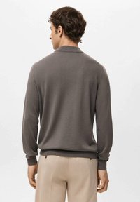 Szary sweter z dzianiny z kołnierzem i długimi rękawami. Posiada ściągacze na mankietach i dole, gładką fakturę oraz minimalistyczny design.