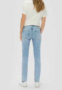 Jean en denim bleu clair avec une coupe slim, cinq poches et des détails de couture subtils. Le tissu paraît lisse avec une taille confortable.