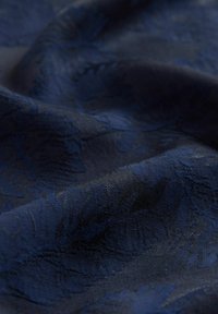 Strukturierter marineblauer Stoff mit einem dezenten Blumenmuster. Das Material wirkt weich mit einem leichten Glanz und hat einen glatten, fließenden Fall.