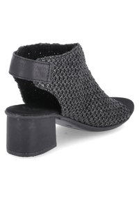 Sandale à talon en tissu noir tissé avec un dos ouvert et un talon épais, offrant une finition texturée et des accents lisses.