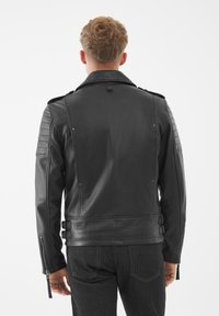 Giacca da motociclista in pelle nera con rifiniture trapuntate sulle spalle e fibbie laterali. Presenta un colletto a punte e polsini con zip.