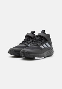 Schwarze Sportschuhe mit einem atmungsaktiven Mesh-Obermaterial, Gummisohle und reflektierenden Akzenten. Mit Schnürsenkeln und einem Klettverschluss für eine sichere Passform.