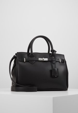 Sac à main en cuir noir avec deux anses, bandoulière réglable, détail de boucle argentée et petite pochette attachée, posé sur un socle blanc.