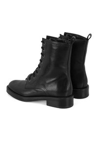 Bottines en cuir noir avec une finition texturée, bout rond, système de laçage et un petit talon solide. Présente des languettes à l'arrière.