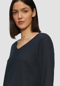 Maglione a maglia strutturata blu navy con scollatura a V e maniche lunghe, caratterizzato da una vestibilità rilassata e da sottili motivi orizzontali.