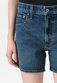Denim shorts in mid-blue met een hoge taille, vijf-pocket ontwerp en contrasterende stiksels. Voorzien van een knoopsluiting en een rafelige zoom.
