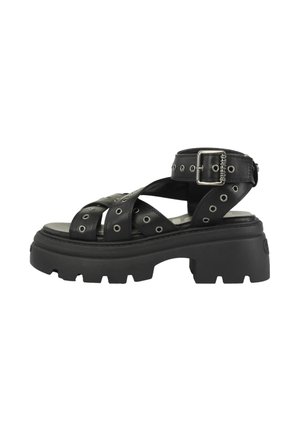 Sandale plateforme noire à semelle épaisse avec des brides croisées épaisses ornées d'œillets métalliques et une fermeture à boucle à la cheville sur une semelle robuste.