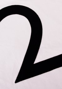 Zwart-wit textiel met een groot, gedurfd, gebogen zwart vorm op een witte achtergrond, met een gladde, zachte textuur.