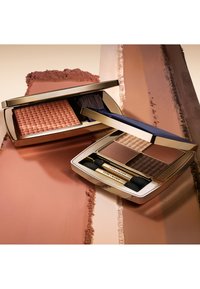 Compact makeup palette with a woven blush in pink and two bronzer shades in a sleek gold case. Included brush and applicators.