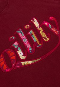 Bordeaux sweatshirt met grote geborduurde "Oilly" letters gevuld met een multicultureel bloemenpatroon. Zachte textuur, crew neck ontwerp.