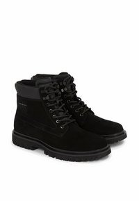 Stivali alla caviglia in suede nero con design lacciato, colletto imbottito, suola in gomma robusta e un logo discreto sul lato.