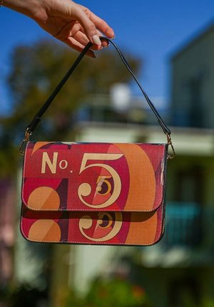 Bunte Lederhandtasche mit einem markanten grafischen Design in Rot- und Orangetönen, und dem Text "Nr. 5" deutlich sichtbar.