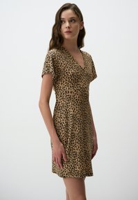Leopardprint jurk in beige en zwart, met een v-hals en korte mouwen, gemaakt van zachte, rekbare stof met een getailleerde pasvorm.