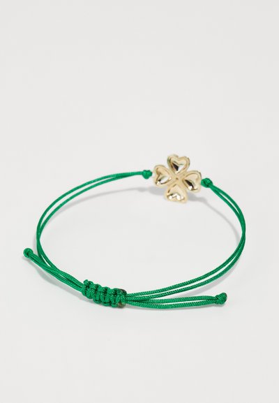 Green cord bracelet with adjustable knot, featuring a gold clover charm with heart-shaped leaves. Smooth texture, simple design.