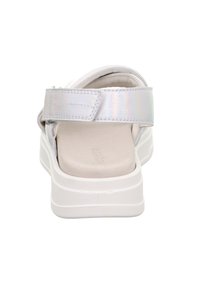 Biała sandałka z opalizującym paskiem i regulowanym zapięciem na rzep. Posiada miękką wkładkę i masywną białą podeszwę.