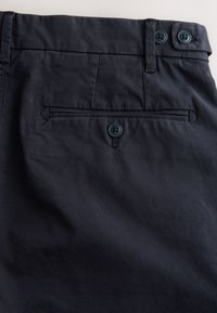 Shorts bleu marine en tissu léger, présentant un devant plat, des poches latérales et une poche arrière avec fermeture à bouton.