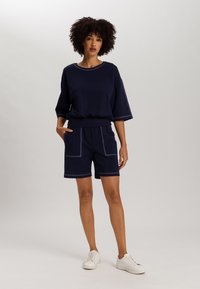 Top in cotone blu navy con maniche corte e orlo a costine, abbinato a pantaloni corti coordinati con due tasche frontali e cuciture a contrasto.