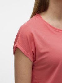 Close-up of a person wearing a coral short-sleeve shirt with a rolled cuff on the sleeve against a white background.