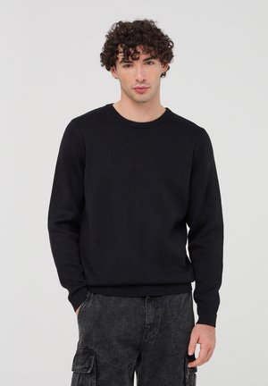 Maglione nero a maglia con collo rotondo, maniche lunghe e polsini e orlo a coste; finitura testurizzata e vestibilità comoda.