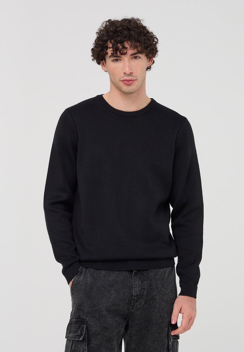 Maglione nero a maglia con collo rotondo, maniche lunghe e polsini e orlo a coste; finitura testurizzata e vestibilità comoda.