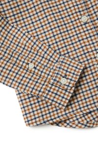 Geruite flanellen shirt met patronen in bruin, blauw en crème, met knoopmanchetten en een zachte textuur. De knopen zijn crème-kleurig en rond.