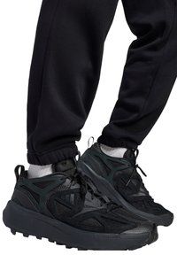 Schwarze Sportschuhe mit atmungsaktivem Mesh und synthetischem Obermaterial. Verfügen über strukturierte Akzente, gepolsterte Sohlen und ein sicheres Schnürdesign.