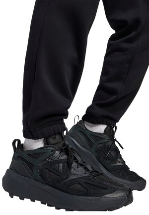 Schwarze Sportschuhe mit atmungsaktivem Mesh und synthetischem Obermaterial. Verfügen über strukturierte Akzente, gepolsterte Sohlen und ein sicheres Schnürdesign.