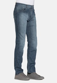 Jeans in denim di colore azzurro chiaro, design a gamba dritta con cinque tasche, leggera scoloritura e dettagli in metallo. Abbinati a sneaker grigie.