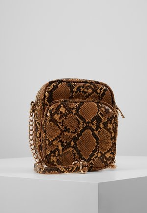 Pieni ruskea ja musta käärmeenahkakuviollinen olkalaukku, jossa etutasku ja kultainen ketjuhihna, valkoisella jalustalla.