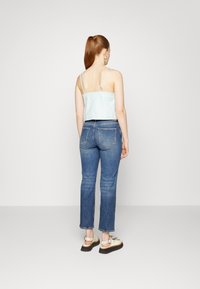 Zkrácený světle modrý top s tenkými ramínky, doplněný o džíny s vysokým pasem a platformové sandály se cvočky. Jednoduchý a ležérní outfit.